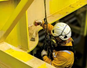 Worker applying protective coating using a harness