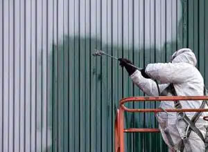 Worker spray painting wearing a white protective suit